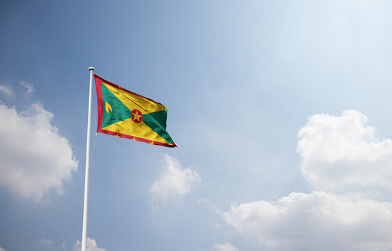 Grenada flag waving in sky with long mast.