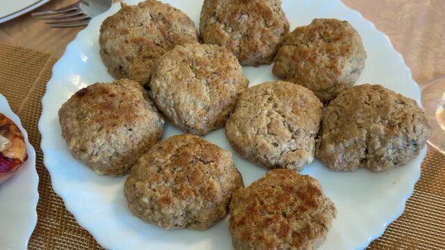 Close-up homemade pork beef patties baked on white plate festive table, golden browned crust with breadcrumbs, linen placemat