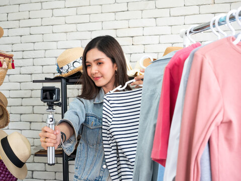 Young Asian Female Fashion Blogger Recording Clothing Review with Action Camera in Home Studio, Woman Influencer Presenting Casual Apparel for Social Media Content and Online Shopping Promotion