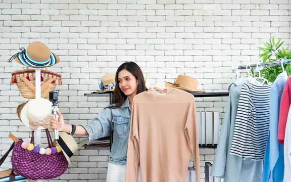 Asian Female Fashion Influencer Recording Clothing Review Video at Home Studio, Young Woman Creating Social Media Content with Camera and Casual Apparel for Online Shopping Promotion