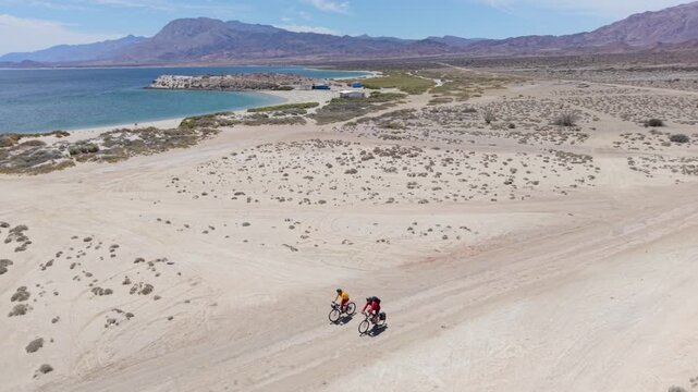 Mature man and woman enjoy biking near La Gringa, taking in the views of Bahia De Los Angeles and the Sea of Cortez in Baja California, Mexico
