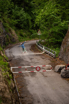Ein Skateboarder macht einen Powerslide auf einer geschlossenen Waldstrasse