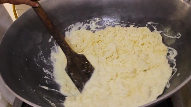 An unrecognizable person is adding liquid whey to a cheese mixture to produce traditional Quesillos inside a factory in Yaguara, Huila, Colombia. Concept of handmade and Colombian food