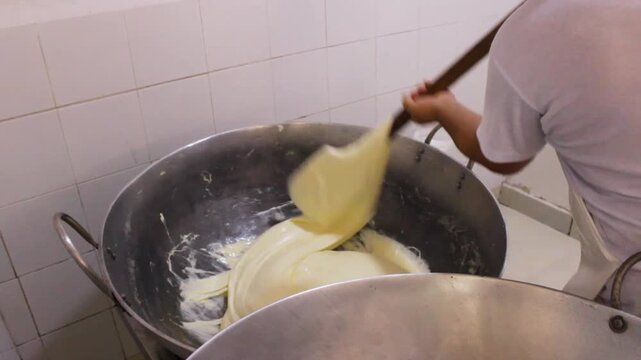 An unrecognizable man is spinning a delicious cheese for the production of a typical Colombian Quesillo inside a factory in Yaguara, Huila, Colombia. Concept of artisanal food and handmade 