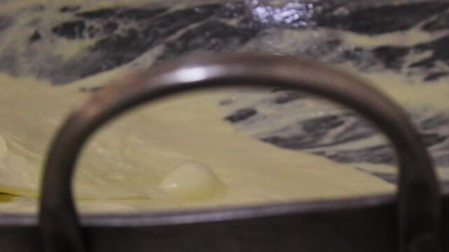 Detail of a cheese mixture being melted on a flat surface to produce the typical and delicious Colombian Quesillo inside a factory in Yaguara, Huila, Colombia. Concept of artisanal food