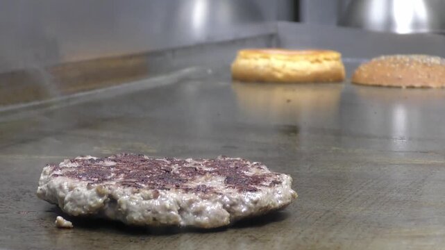 Preparazione di un panino hamburger su piastra. Panino hamburger grigliato con pancetta, cipolla glassata, formaggio e uova