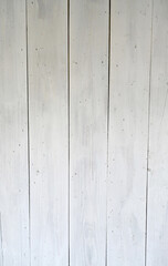 Obraz premium Weathered white wash painted board surface with vertical boards showing worn paint, visible wood grain, knots, cracks, gaps between boards, many nail heads, and light shadow at the top