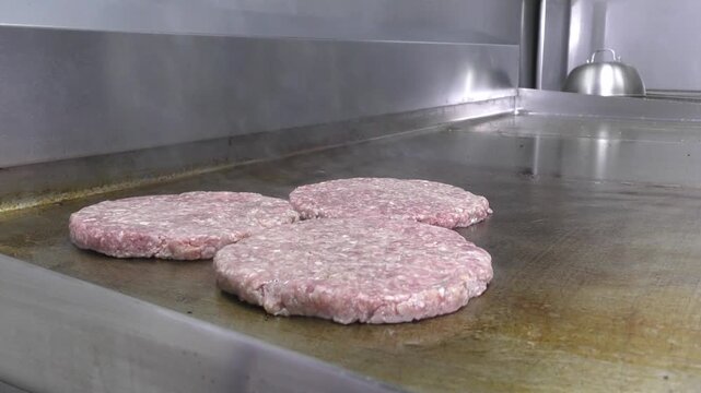 Preparazione di un panino hamburger su piastra. Panino hamburger grigliato con pancetta, cipolla glassata, formaggio e uova