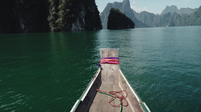 Cinematic Vertical Tilt-Up from Traditional Longtail Boat Prow with Ribbons to Majestic Limestone Mountains and Emerald Lake, Khao Sok National Park, 4k Video