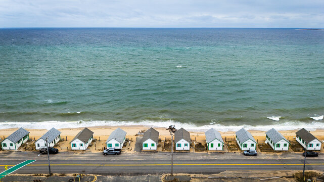 Aerial view of the iconic Days Cottages lined up along the sandy beach and the Atlantic Ocean in Truro, Cape Cod, Massachusetts, United States.