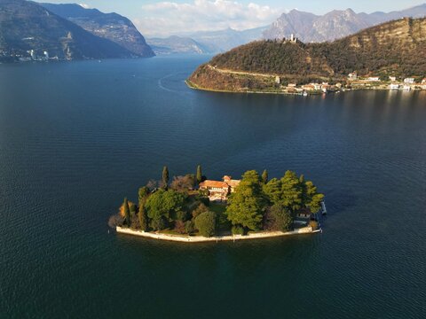 Aerial view of the historic villa on Isola di Loreto surrounded by lush trees on Lake Iseo with Monte Isola in the background Monte Isola, Lombardy, Italy.
