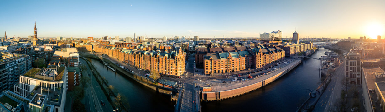 Aerial view of the Speicherstadt district with historic red brick warehouses and canals under a golden sunset sky in Hamburg, Hamburg, Germany.