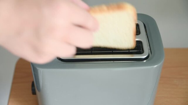 Grey toaster with glowing heating elements toasting bread slices on wooden countertop