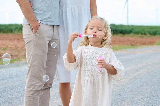 Family moment captured outdoors with a child blowing bubbles on a path