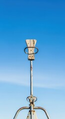 Fototapeta premium Weathered metal and wood seesaw standing high against a bright blue summer sky, symbolizing balance, movement, and nostalgic youth games, youth, balance, low