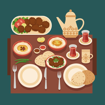 An overhead view of a traditional Middle Eastern breakfast or lunch spread featuring falafel, hummus, flatbread, and tea served on a wooden table.