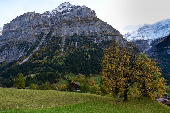 Autumn alpine cliffs and glacier with chalet in valley