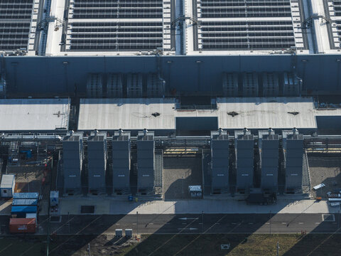 Aerial view of an AI data center with cooling towers and cloud computing hub exterior featuring rooftop infrastructure and industrial cooling systems.