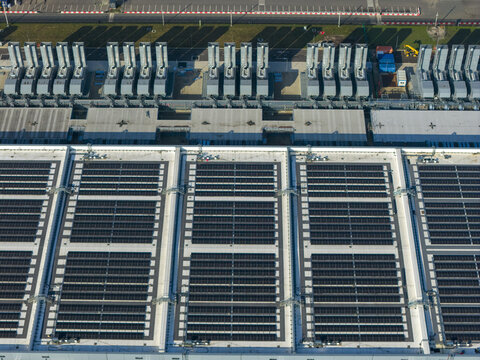 Aerial view of an AI data center with cooling towers and cloud computing hub exterior featuring solar panels on the roof.