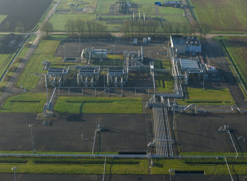 Aerial view of the natural gas mining facility with complex pipelines, storage tanks, and industrial infrastructure surrounded by rural fields in Slochteren, Groningen, Netherlands.