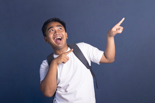 Young student with a backpack pointing up with an excited and happy facial expression.