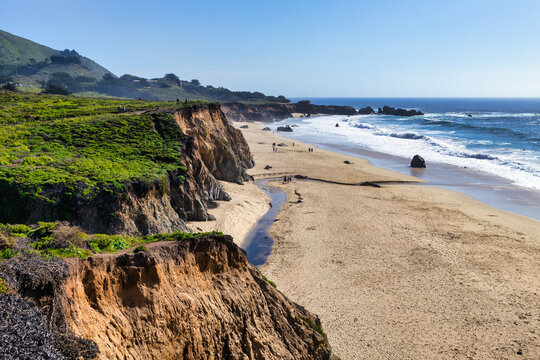 Scenic coastal cliffs and sandy shoreline at Garrapata Beach along Highway 1 in Big Sur, California, with waves, ocean view, and people enjoying the rugged Pacific coastline