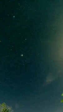 A cloudy night sky is dotted with stars, peeking through the breaks in the cloud cover, creating a celestial, ethereal, and slightly mysterious scene.