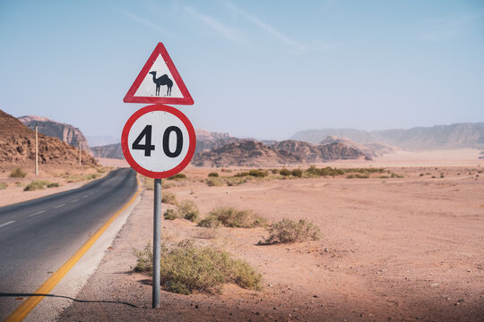 Ein Verkehrsschild mit dem Tempo 40 und einem Kamel Warnhinweis steht am Stra&szlig;enrand einer Stra&szlig;e, die durch die W&uuml;ste Wadi Rum in Jordanien f&uuml;hrt