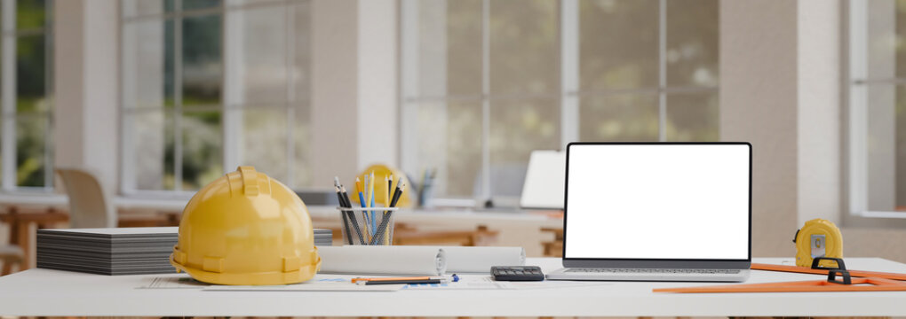 Modern engineering desk with blank laptop screen safety helmet and drafting equipment in office