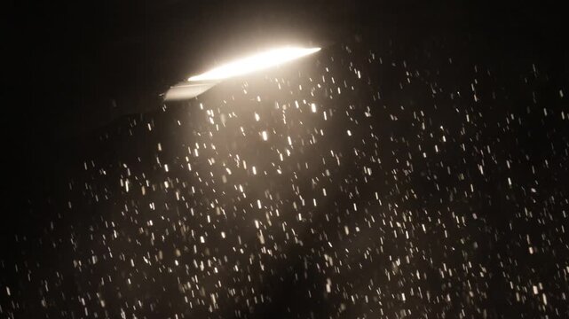 Snowfall against the background of light from a street lamp at night
