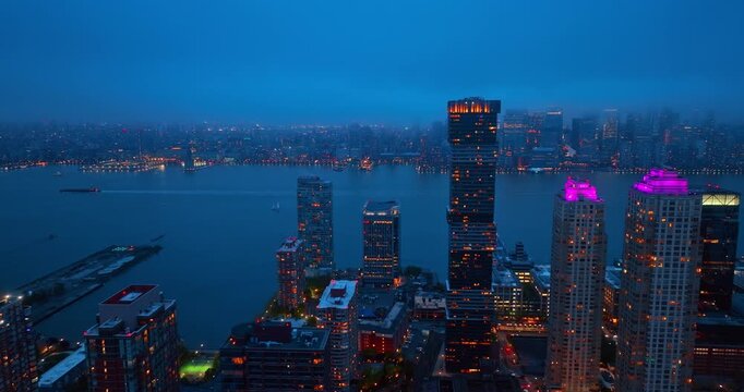 Dusk time footage over beautiful Jersey City from drone. Thick cloudscape covers the scenery of Manhattan.