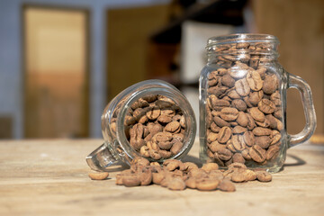 Fototapeta premium Roasted Coffee Beans Spilling from Glass Mason Jars on Wooden Cafe Table