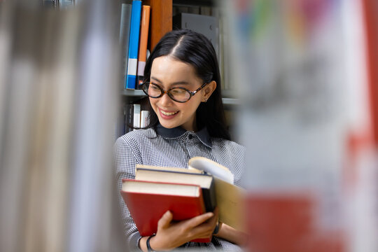 Young Asian woman studies in quiet library. Books line tall shelves behind. she holds  book, eyes focused. Serene atmosphere, calm concentration. Ideal for educational or study-themed projects
