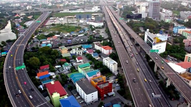 Aerial view of a bustling highway interchange in an urban landscape, featuring multiple lanes of moving traffic and surrounding city buildings at dusk.