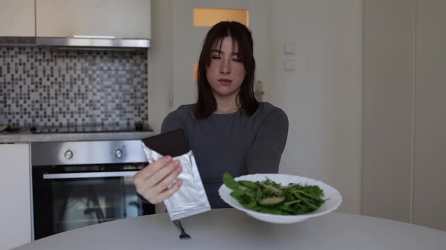 Young woman with disordered eating mindset compares healthy salad and chocolate treating food as strictly good or bad while struggling with guilt and cravings