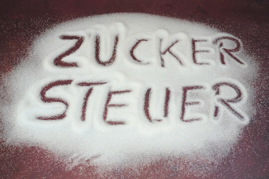 Verteilter Zucker mit Inschrift Zuckersteuer die demn&auml;chst auch in Deutschland eingef&uuml;hrt werden soll
