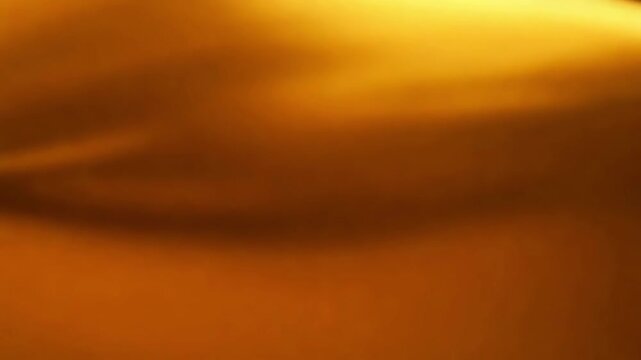 An abstract golden background features a beautiful sunset cloudscape where bright orange and red light glows across the horizon during a nature inspired Cinematic gold abstract background video