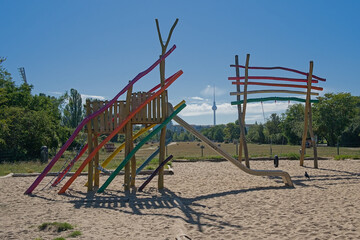  Playground with colorfull wood constructions, slide and swing set, with Fernsehturm television tower in the background in Mauerpark, Berlin, Germany  © Kristof Lauwers