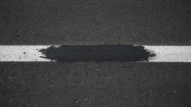 overpaint. Close-up of a white road line on asphalt, a section painted over with black. mobility guides, transit brochures, designed for mobility and urban transit guides.