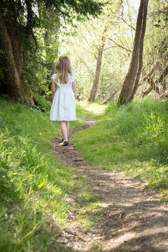 Little girl walking alone through forest path, depersonalization