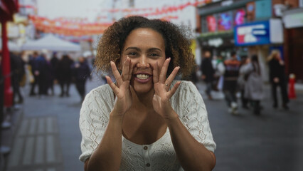 Fototapeta premium Woman cups hands to mouth calling to passersby on a busy outdoor street market; joy connection community.