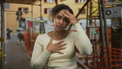 Obraz premium Woman clutching chest with hand and touching forehead in building under construction; anxiety safety.