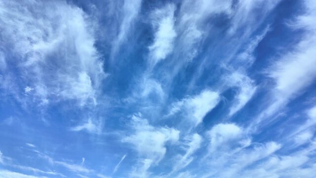 Timelapse of white cirrus clouds moving across deep blue sky in clear weather