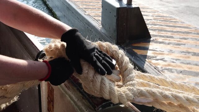 Sailor Hand Securing Rope to Mooring Bollard on Boat