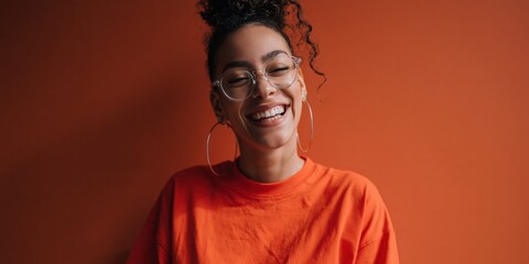 Obraz premium Young woman laughing and smiling against orange backdrop
