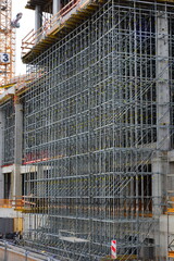 A high-rise concrete building completely covered by complex construction scaffolding © Wolf Steppe