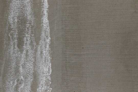 white efflorescence salt deposits on a grey concrete wall.