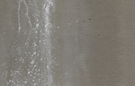 Close-up of white efflorescence salt deposits on a grey concrete wall.