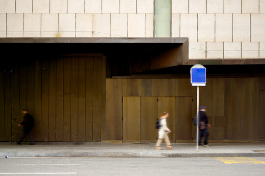 Blurred People Walking Past a Dark Modern Building Wall