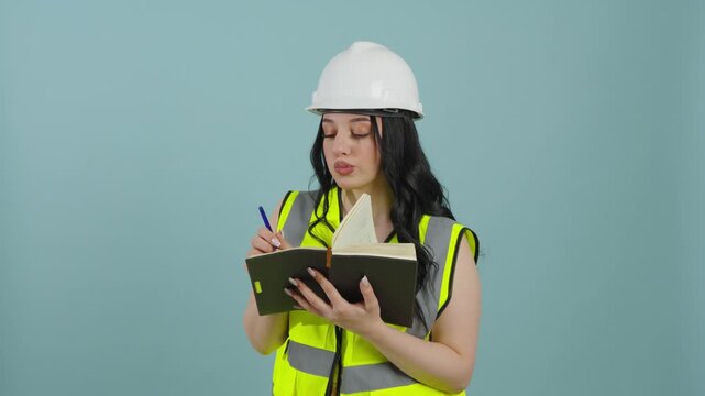 Female engineer in safety vest writing in a notebook